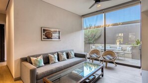 Ein modernes Wohnzimmer mit einer Couch, zwei Korbstühlen, einem Glastisch und einem Deckenventilator.
