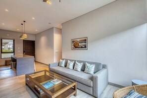 Una sala de estar moderna con un sofá, una mesa de centro y una zona de comedor al fondo.