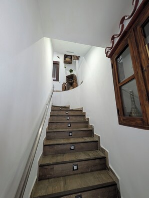 A wooden staircase with handrails, a small window with a decorative frame, and a plant in the background. - Luminous Duplex centrally located in Arroyo de la Miel, 3 minutes from downtown. (Benalmádena)