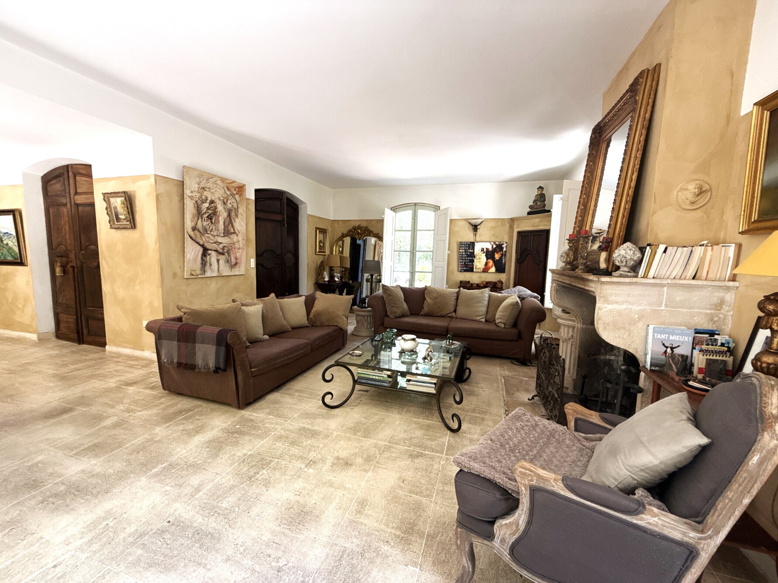 Ein geräumiges Wohnzimmer mit einem braunen Sofa, einem Glastisch und einem Kamin.