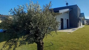 A modern building with a flat roof, a small tree in the foreground, and a clear blue sky.
