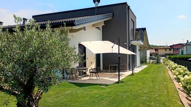 A modern house with a patio, outdoor furniture, and a well-maintained lawn.