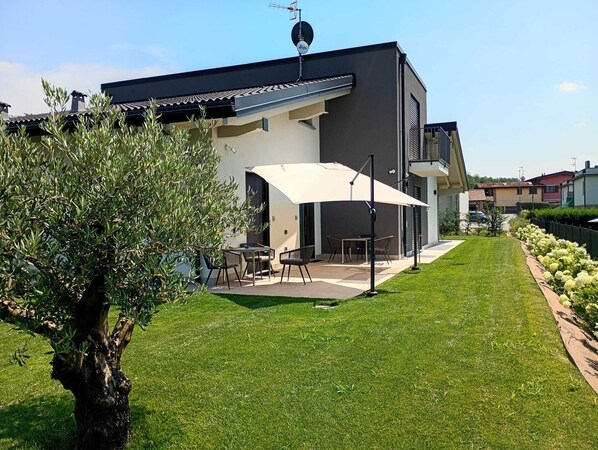 A modern house with a patio, outdoor furniture, and a well-maintained lawn.