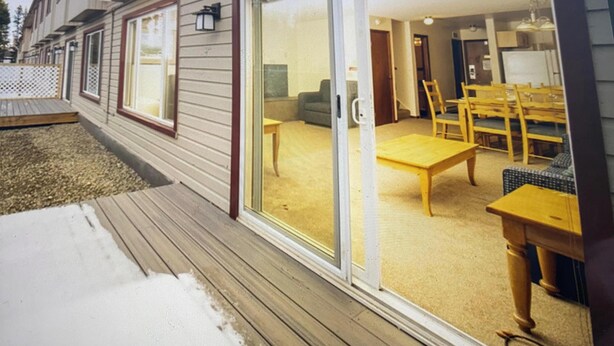 A house with a sliding glass door leading to a living area with a sofa, table, and chairs.