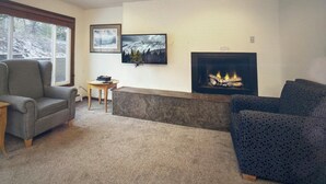A living room with a fireplace, two framed pictures, a sofa, and a chair.