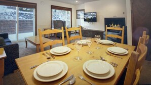 A dining area with a table set for four, chairs, a television, and a fireplace.