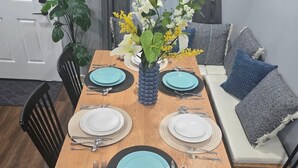 Une table à manger dressée avec des assiettes, des couverts et un vase rempli de fleurs.