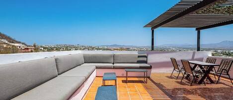 An outdoor patio with a sectional sofa, a small table, and a dining set.