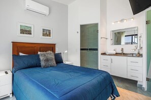 Une chambre à coucher comprenant un lit, une table de chevet et une salle de bain avec un lavabo et un miroir.