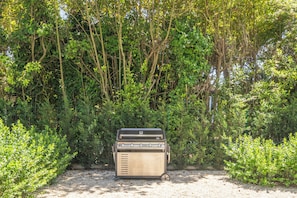 Ein tragbarer Grill in einer natürlichen Umgebung mit dichtem Grün im Hintergrund.