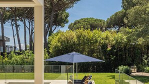 A poolside area with a glass enclosure, a lounge chair, and a blue umbrella. - Villa Smeralda (Marina di Pietrasanta)