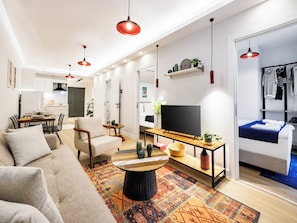 A modern living room with a sofa, a coffee table, a TV, and a dining area with chairs and a table. - 5 min Walk to Taksim Square & Galata Sleeps 6 (Istanbul)