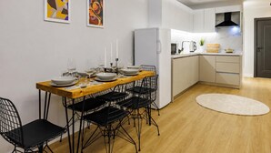 A modern kitchen with white cabinets, a wooden dining table, black wire chairs, and a red pendant light. - Glamorous Cihangir 3 Bedrooms Apt At Monnas Suite (Istanbul)