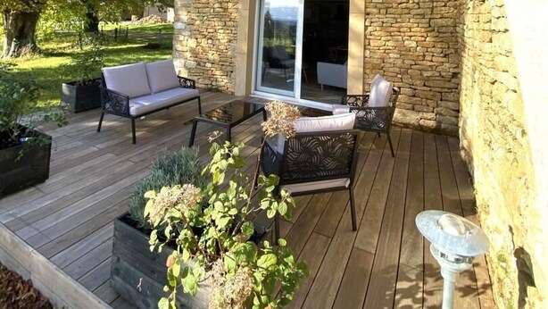 Ein Steinhäuschen mit einer Terrasse, einer Bank und einem Blumentopf.