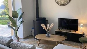 Ein modernes Wohnzimmer mit einer Couch, einem Fernseher, einem Kamin und einer Wanduhr.