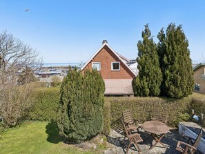 Ein Haus mit rotem Dach, einem kleinen Fenster und einer Terrasse mit Holzmöbeln.