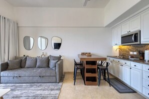 Eine moderne Küche mit weißen Schränken, einer Mikrowelle und einem Essbereich mit Tisch und Stühlen.