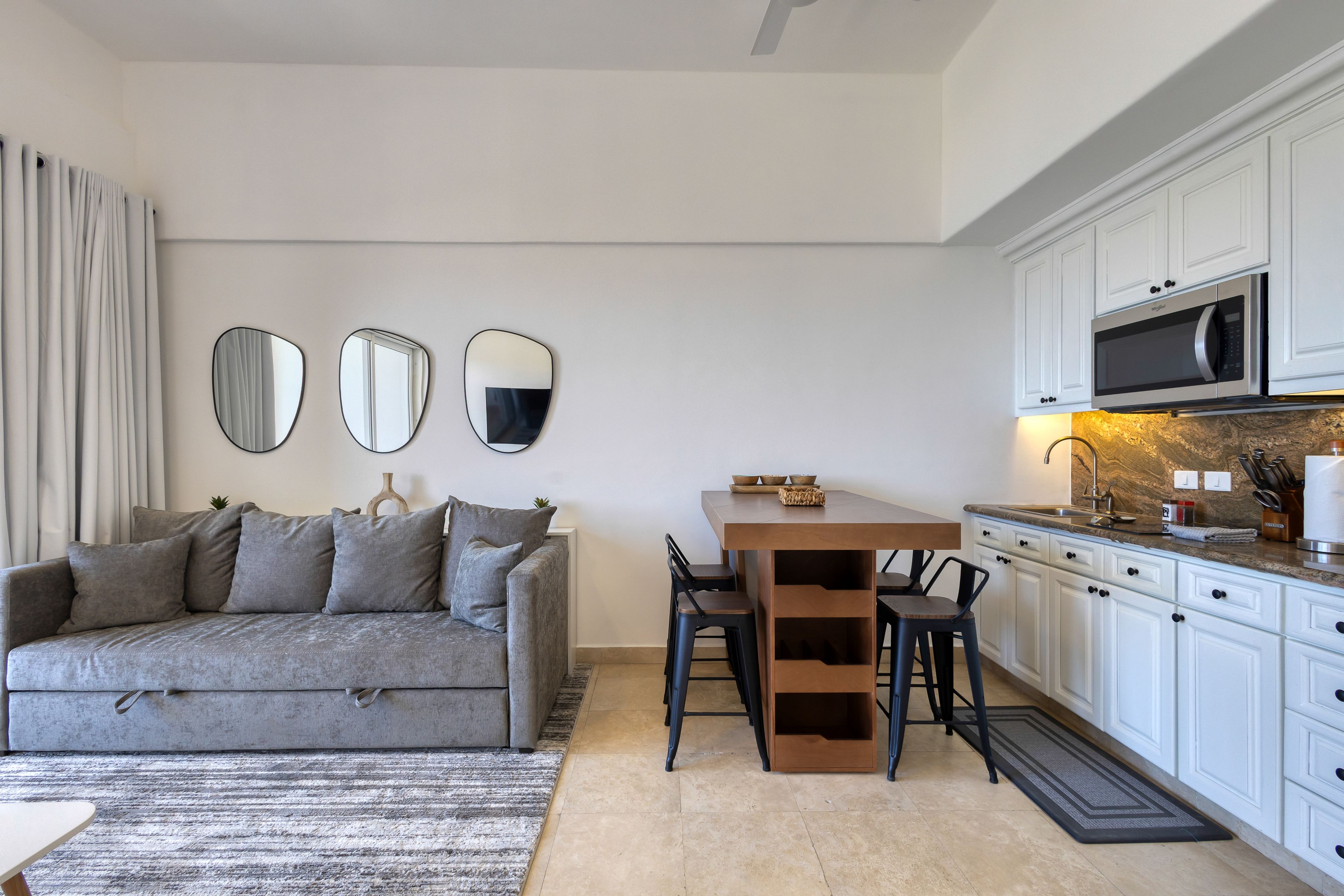 A modern kitchen with white cabinets, a microwave, and a dining area with a table and chairs.