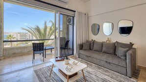 A modern living room with a sofa, a coffee table, and a chair. There are three wall mirrors and an air conditioning unit. - Stylish Coastal Retreat With Breathtaking Views, Resort Pool & Private Balcony (Cabo San Lucas)
