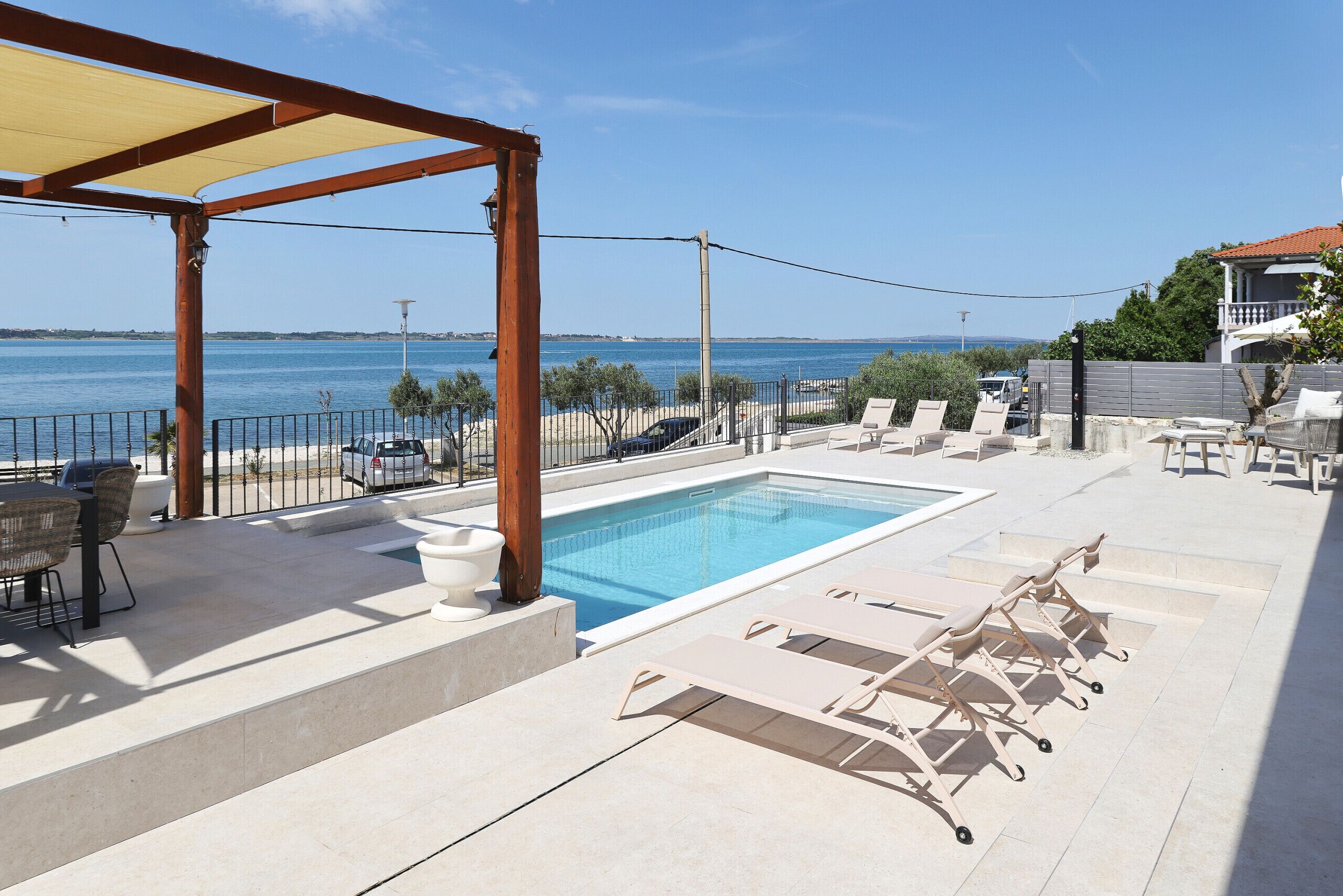 Un espace piscine aménagé avec des chaises longues, une table et une pergola.