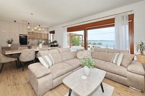 Ein modernes Wohnzimmer mit einem beigen Sofa, einem Couchtisch und einem Essbereich mit einem Holztisch und Stühlen.