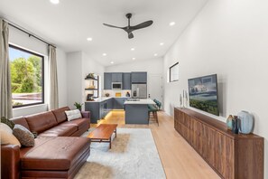 Una sala moderna con sofá, mesa de centro y vista a la cocina.