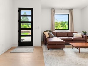 A modern living room with a sectional sofa, a coffee table, and a large window with curtains.