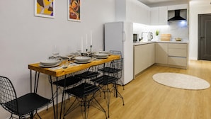 A modern kitchen with white cabinets, a wooden dining table, black wire chairs, and a red pendant light. - Glamorous Cihangir 3 Bedrooms Apt At Monnas Suite (Istanbul)