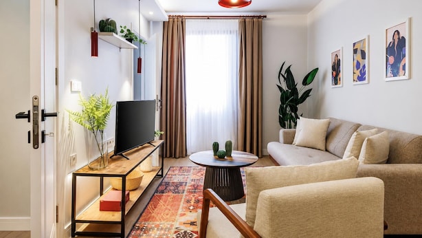 A modern living room with a sofa, TV, coffee table, and decorative plants. - Glamorous Cihangir 3 Bedrooms Apt At Monnas Suite (Istanbul)