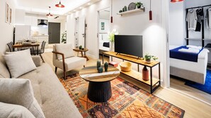 A modern living room with a sofa, coffee table, TV, and a dining area with chairs and a table. - Glamorous Cihangir 3 Bedrooms Apt At Monnas Suite (Istanbul)