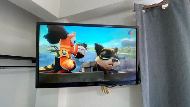 A flat-screen TV mounted on a wall, displaying animated characters. - Hotel Bora Bora (Acapulco)