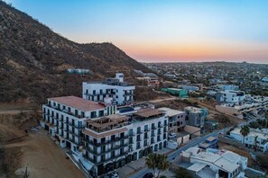Ein mehrstöckiges Hotel mit modernem architektonischen Design, gelegen in einer hügeligen Gegend mit Blick auf die Stadtlandschaft.
