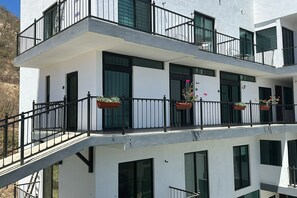 Un edificio de varios pisos con balcones, ventanas amplias y plantas en macetas.