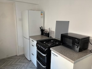 Une cuisine compacte équipée d’un réfrigérateur, d’une cuisinière, d’un four et d’un four à micro-ondes.