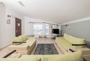 A modern living room with a sofa set, a television, and a view of the outdoors. - Tulip ,Sea-View Fabulous 4-bedroom villa in Kalkan (Antalya)