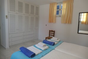 A bedroom with a bed, a chair, a wardrobe, and a window with curtains. - Charming Naxos Villa, Ocean Views, Modern Comfort, Tranquil Escape (Naxos)