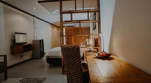 Habitación de hotel pequeña con cama, escritorio con un frutero, televisión y un panel de madera.