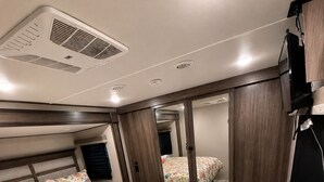 Una camera da letto con due letti, uno specchio, una TV e un termosifone.