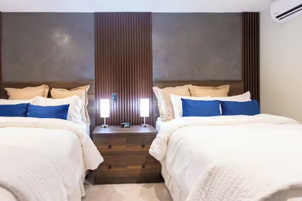 A hotel room with two beds, a nightstand with a clock, and a vertical panel in the center.