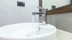 A white bathroom sink with a chrome faucet and a mirror above it.