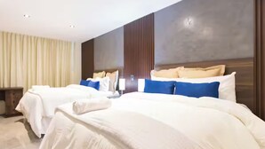 Een hotelkamer met twee bedden, een groot raam met gordijnen, een houten hoofdbord en een tv aan de muur.