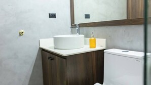 Een badkamer met een witte wastafel, een houten kastje en een toilet.