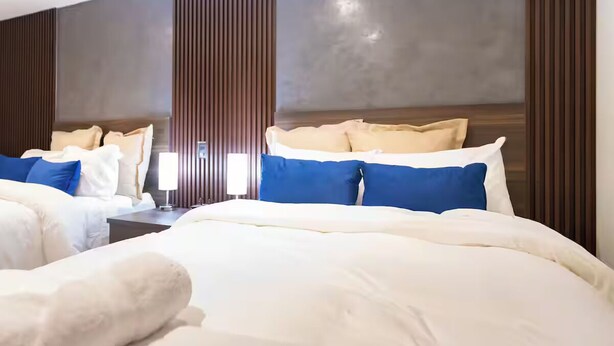 Een hotelkamer met een groot bed, twee nachtkastjes en een wandlamp.
