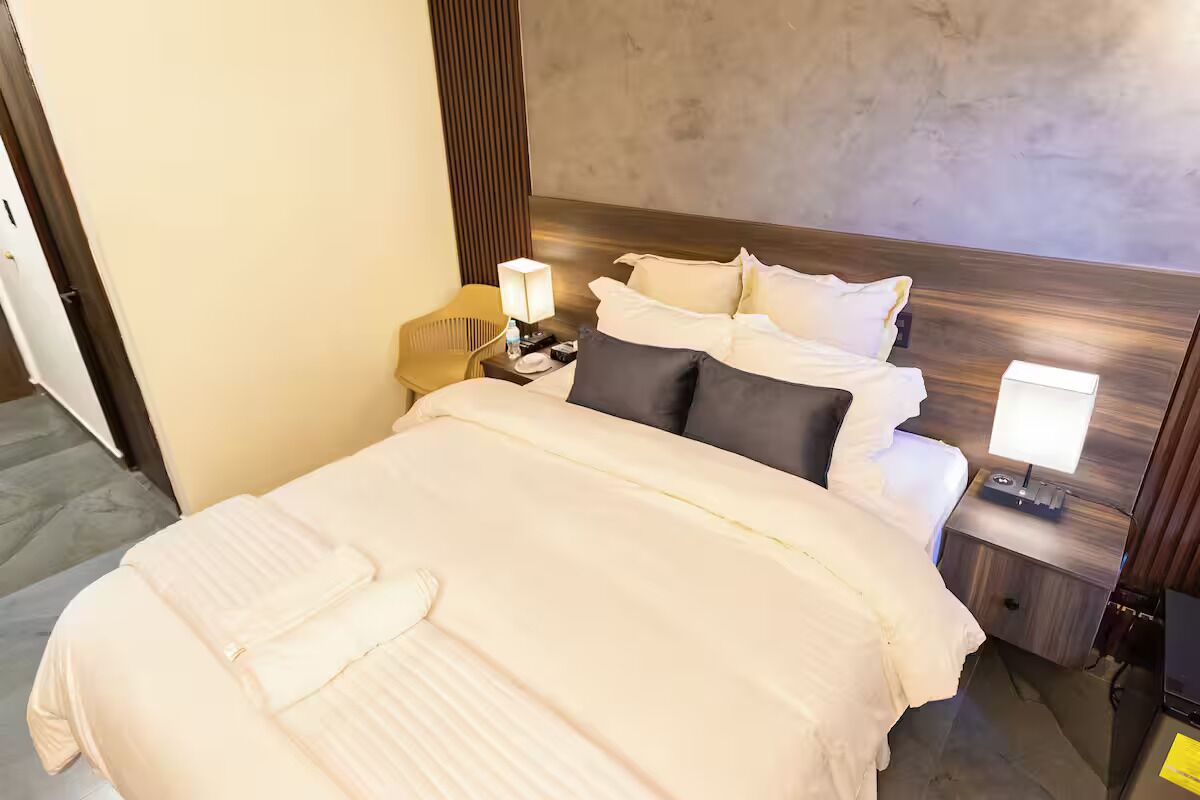Une chambre d’hôtel avec un grand lit, deux tables de chevet, une chaise et une tête de lit en bois.