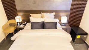 A hotel room with a bed, bedside tables, a chair, and a wall-mounted panel. - Boutique Hotel - Suite Sencilla Ramada (San Salvador)