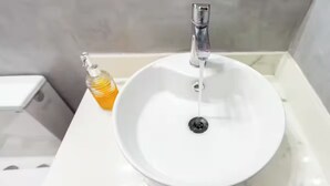 A bathroom with a white sink, a faucet, and a soap dispenser.