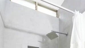 A shower with a square head, a towel rack, and a curtain.