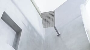 A modern shower with a square, perforated panel.