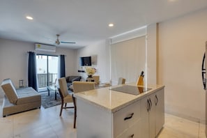 Uma sala de estar moderna com sofá, mesa de jantar e ilha de cozinha.