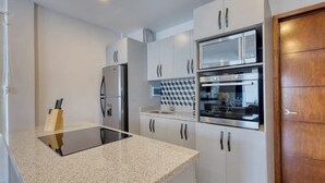 Een moderne keuken met witte kasten, een zwart aanrecht en roestvrijstalen apparatuur.
